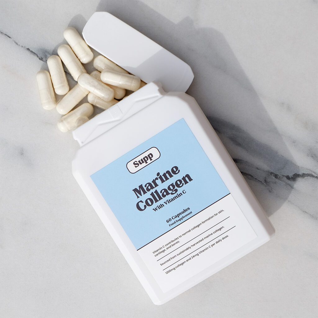 A Marine Collagen bottle spills out capsules onto a marble counter.