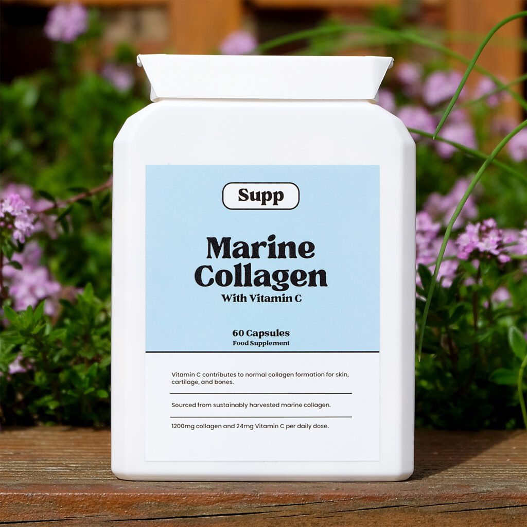 Supp Marine Collagen bottle stood up on a piece of wood against pink flowers.