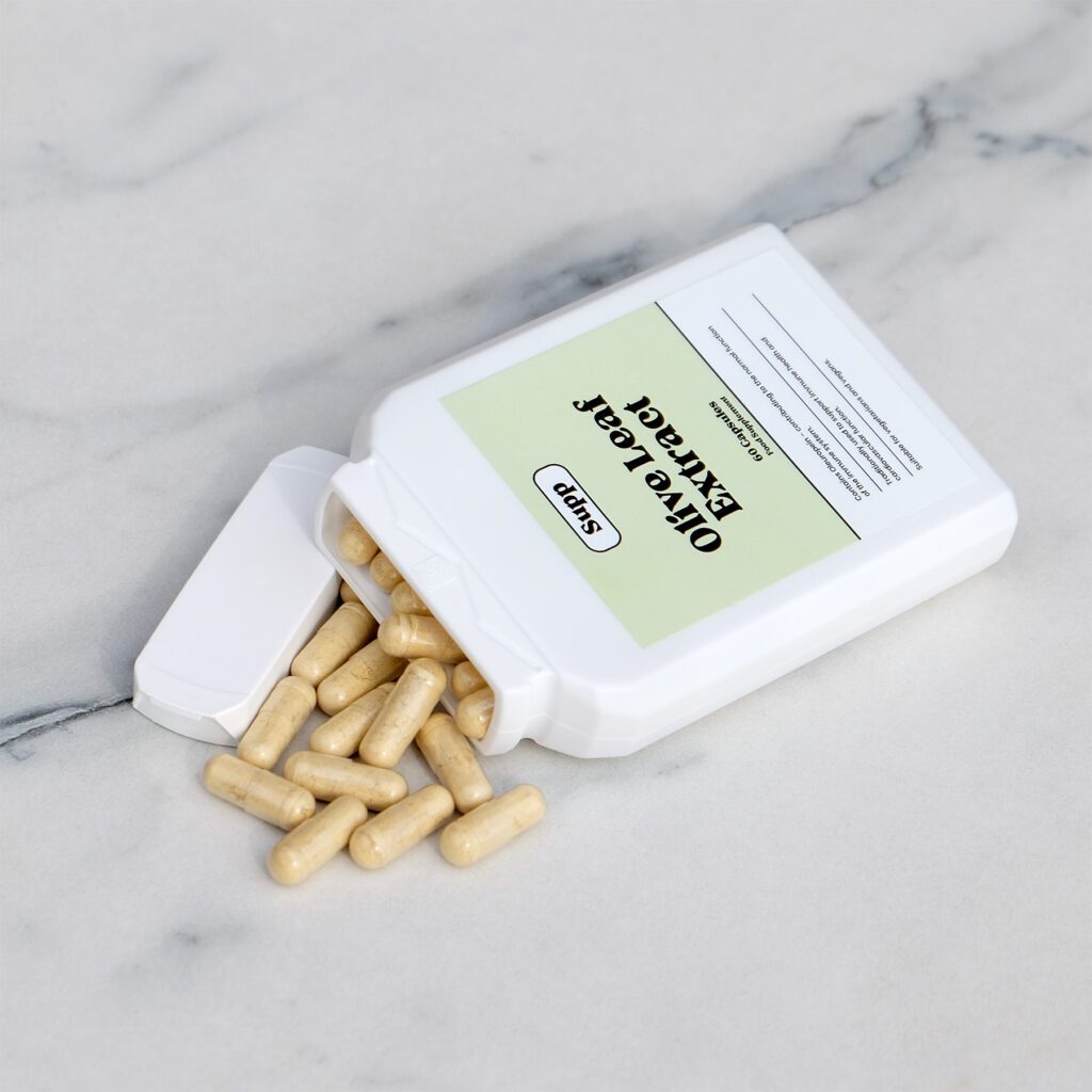 Supp Olive Leaf Extract bottle with capsules spilling onto marble table.