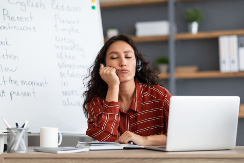 Woman falling asleep at desk with laptop and a coffee on the desk