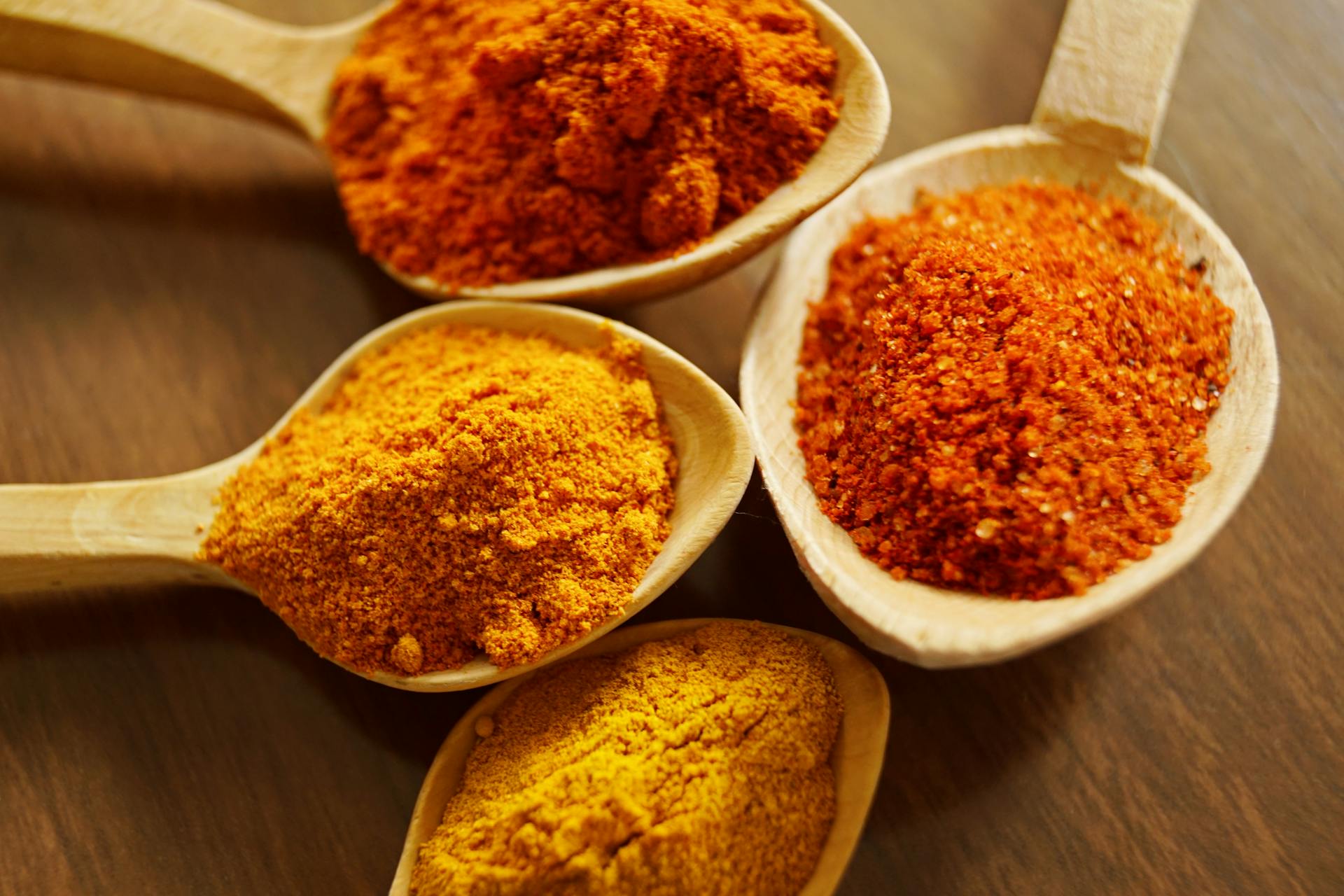 a picture of four wooden spoons with golden turmeric spices