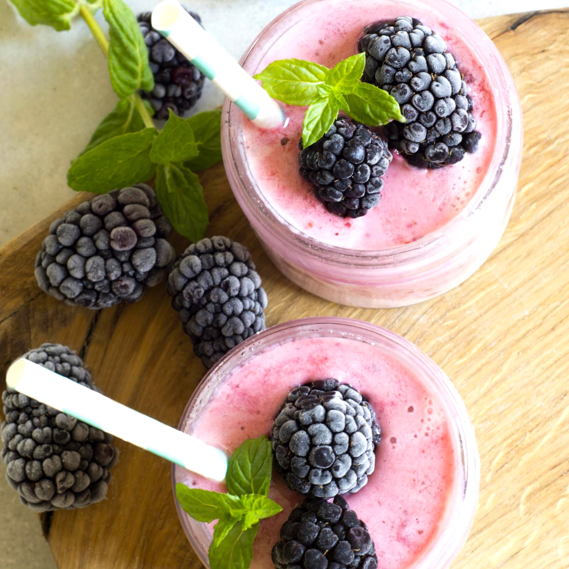 Two berry smoothies with frozen blackberries and mint garnish.