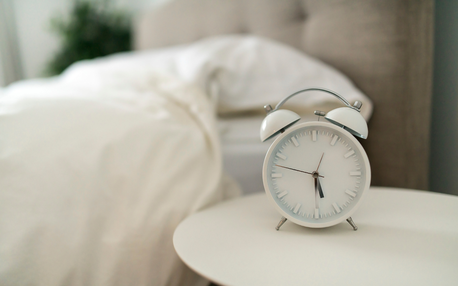 A bright alarm clock next to white bedding.