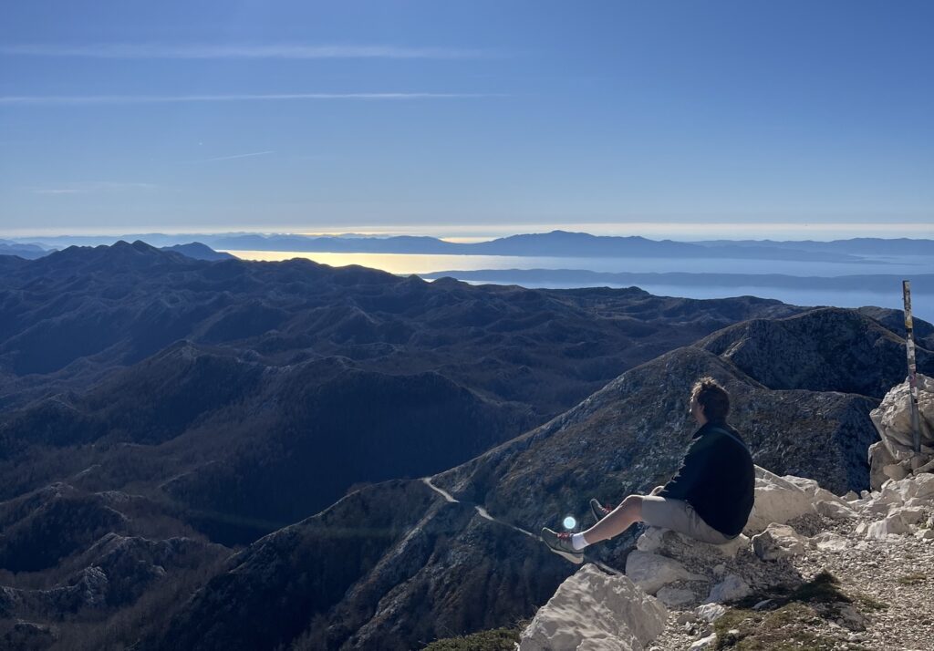 Toby sits high up a mountain after walking.