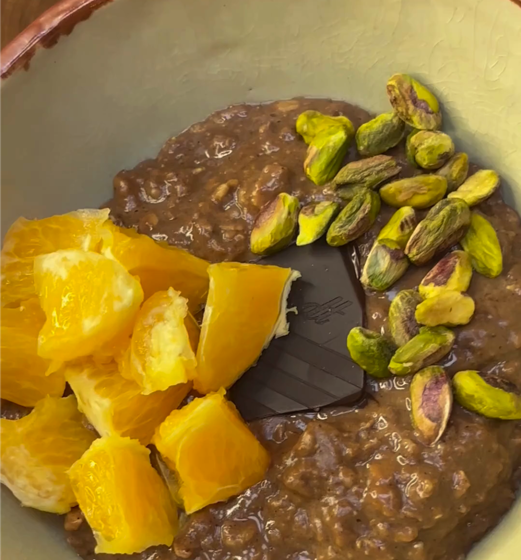 Chocolate orange oats topped with pieces of orange and pistachios.