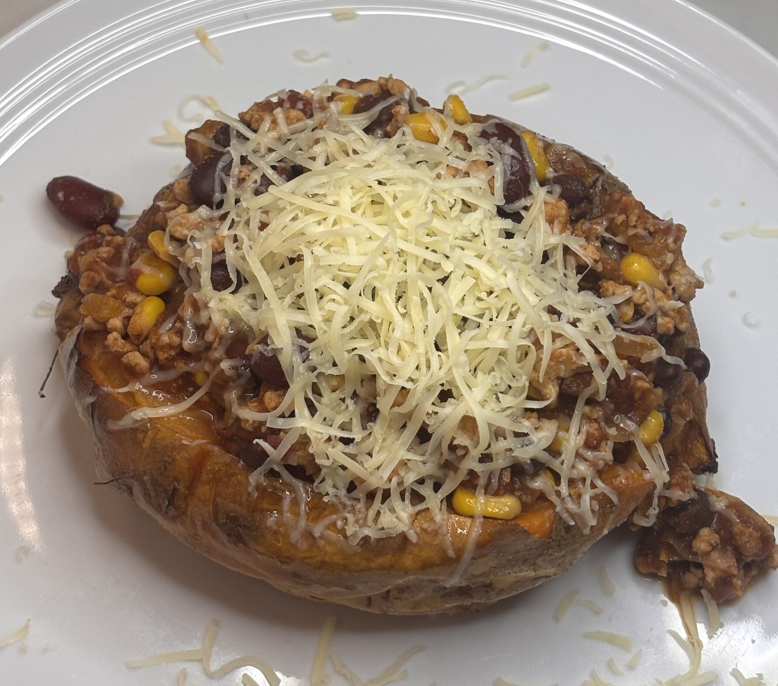 Sweet potato topped with turkey & bean chilli, topped with grated cheese.