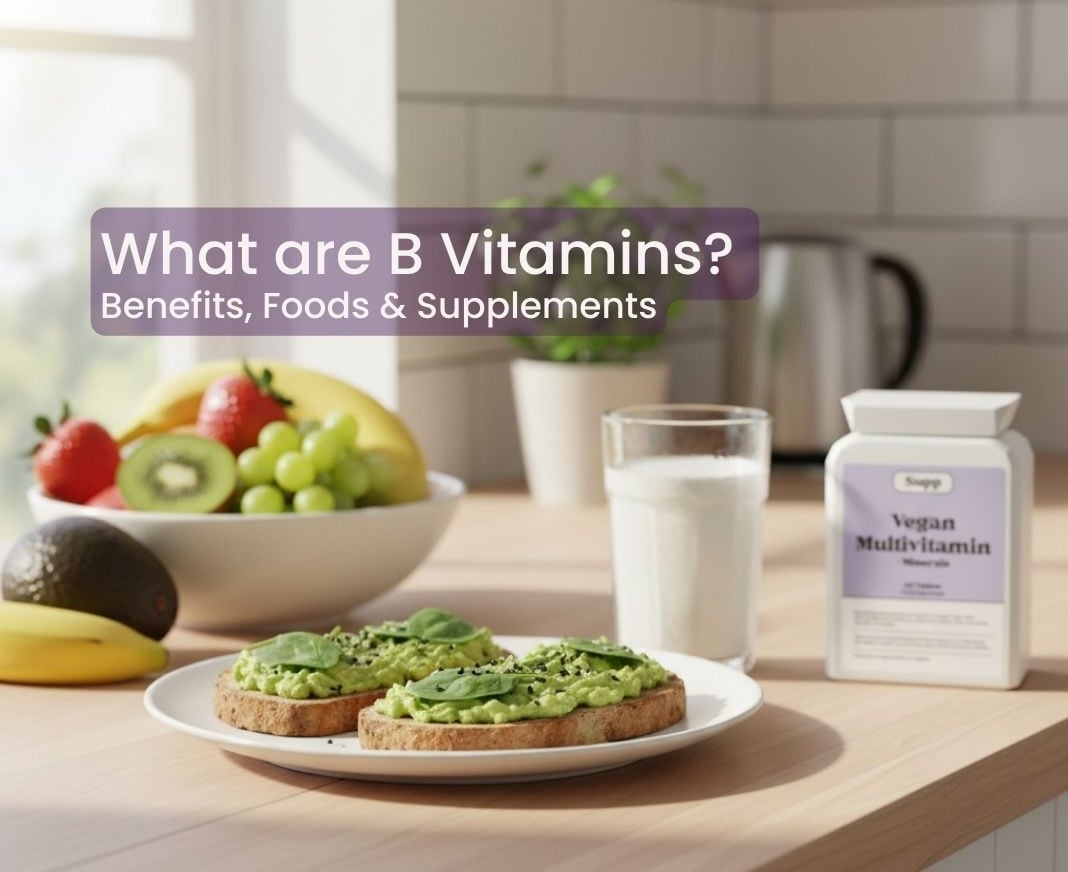 What are B Vitamins Breakfast scene with avocado toast, fruit and a Supp Vegan Multivitamin pack, with text reading ‘What Are B Vitamins? Benefits, Foods, and Supplements’