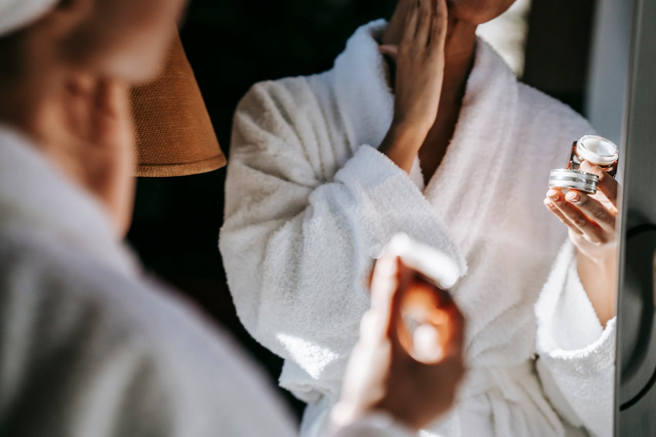 A woman in a dressing gown holding a tub of collagen cream.