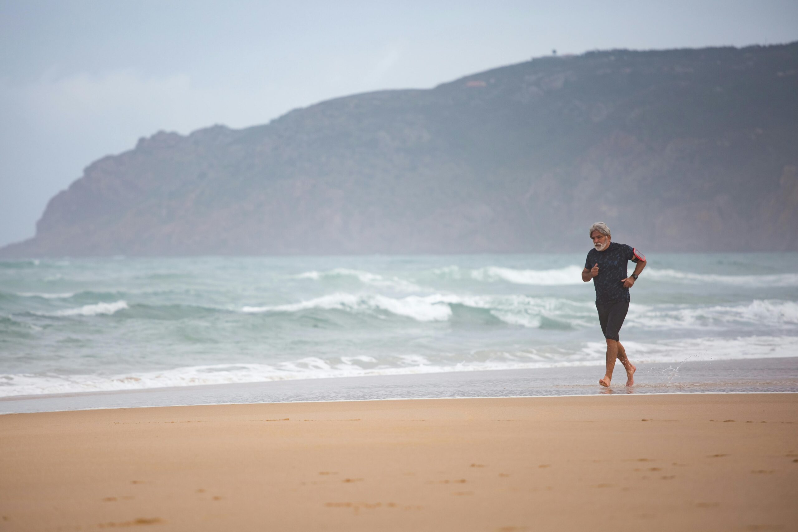 Active man running on a beach, supporting joint health and exercise recovery with green lipped mussel supplement