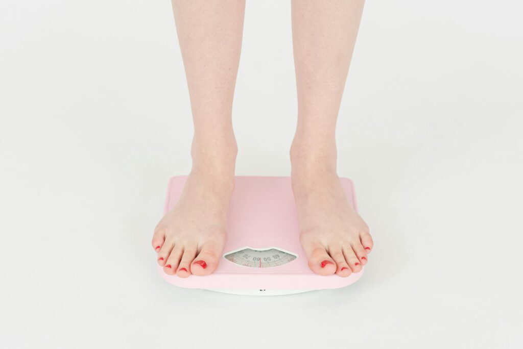 A womans feet stood on pink scales asking does collagen make you gain weight