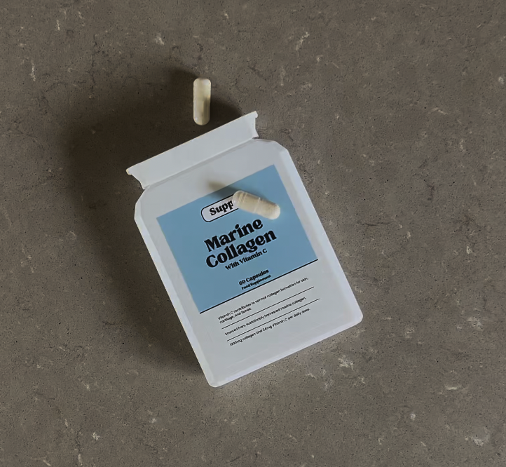 Marine Collagen and Vitamin C Supp's Marine Collagen plus vitamin C supplement bottle laid down on a kitchen worktop with 2 capsules laid on it.
